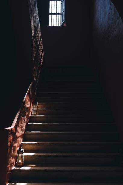 istock Vertical shot of a dark staircase slightly lit by light from a window. 1444071026