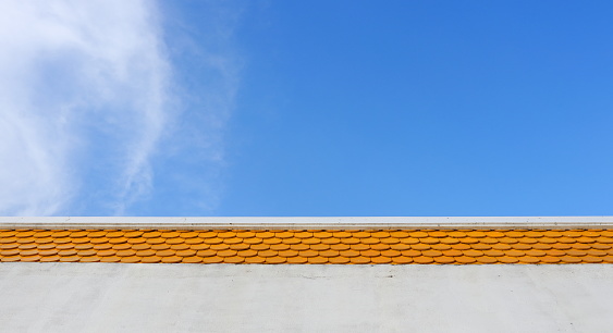 Bright orange color rooftop of building and bright blue sky with cloud.
