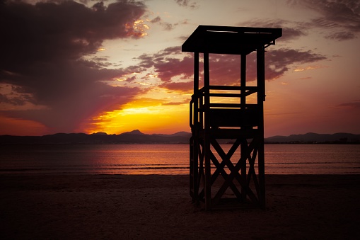 A silhouette of a lifeguard stand at sundown