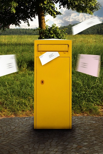 A yellow postbox with letters flying into the postbox to receive old-fashioned mail