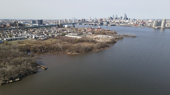 An aerial view from above the Delaware River of North Camden, NJ. The Benjamin Franklin Bridge and Center City Philadelphia are in the background.
