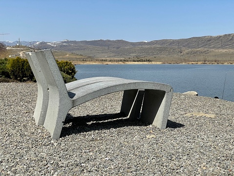 A concrete benches overlooking a calm lake on a sunny day