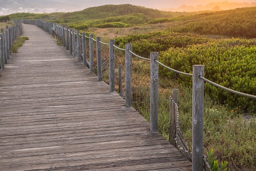 Selective focus. Sunrise view of a wooden walkway on the dunes of a beach