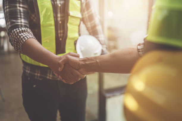 Architect and engineer construction workers shaking hands after finish an agreement in the office construction site, success collaboration concept
