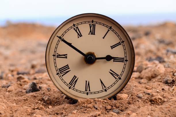 istock Classic analog clock in the sand on a rock desert 1444080679