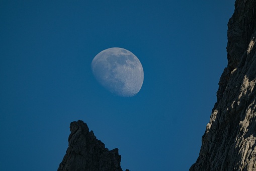 A rocky cliff with the fading moon in the background