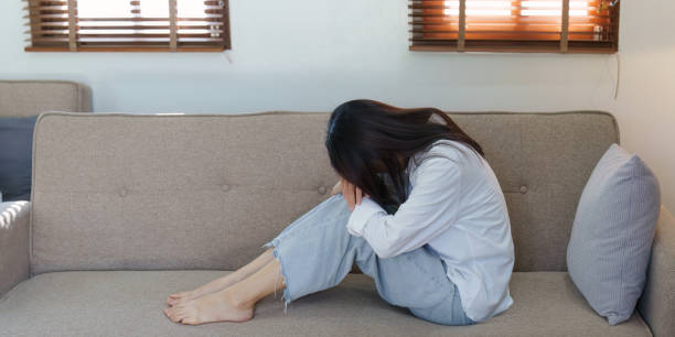 istock Young asian woman feeling miserable and lonely on sofa at home 1444082573