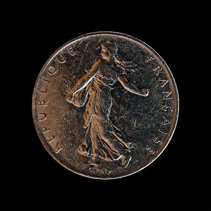 A closeup of a 5 francs coin from 1991 isolated on a black background, the former French national currency