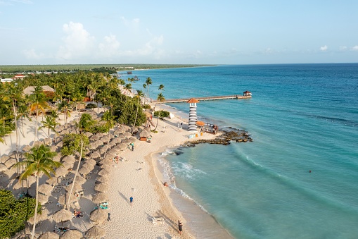 A bird's eye view of a beach with palms and a lighthouse in the Dominican Republic