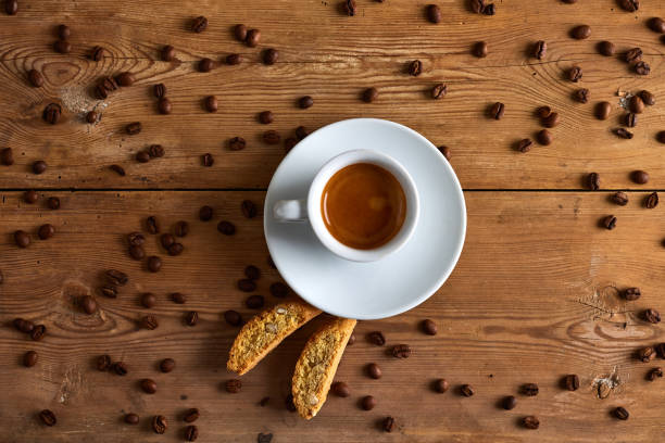 Coffee in cup with spilled seeds and cookie on table with saucer