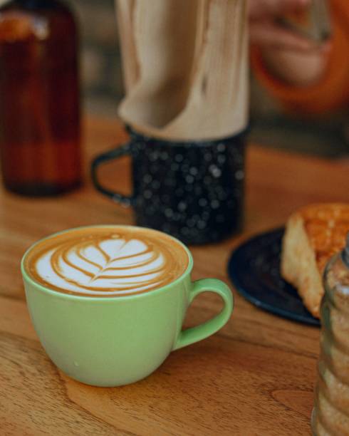 Vertical shot of a cup of latte coffee with a leaf pattern on a wooden table