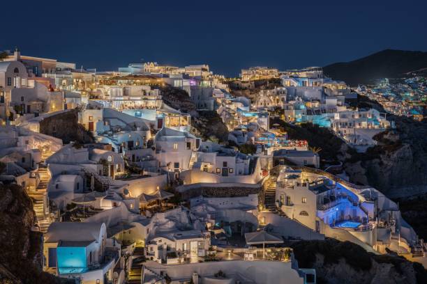 Scenic view at night of Oia village in Santorini, with its typical houses hosting suites Scenic view at night of Oia village in Santorini, with its typical houses hosting suites e boutique hotels illuminated at nighty fira santorini stock pictures, royalty-free photos & images