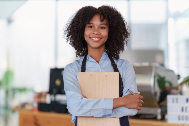 Young Female manager in restaurant with notebook. Woman coffee shop owner with open sign. Small business concept Young Female manager in restaurant with notebook. Woman coffee shop owner with open sign. Small business concept. job retraining stock pictures, royalty-free photos & images