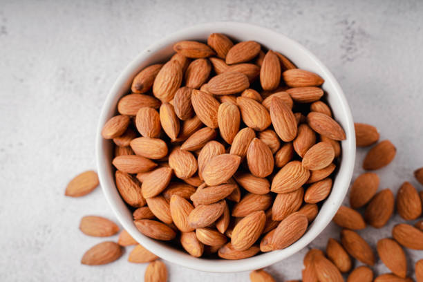 istock Almonds in white porcelain bowl on white table. Almond concept with copyspace. 1444093633