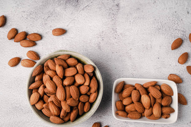 istock Almonds in white porcelain bowl on white table. Almond concept with copyspace. 1444093804