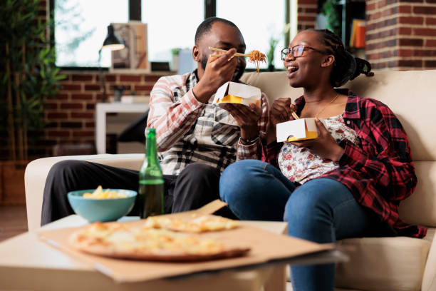 istock Relaxed partners eating noodles from takeout delivery box 1444095502
