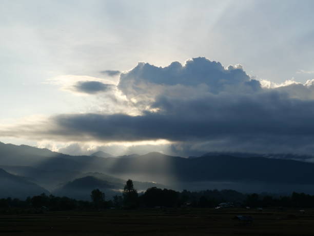istock Silhouette of tree and mountain with sunbeam light shoot through the dark cloud 1444098047