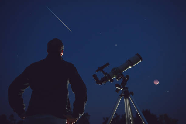 silueta de un hombre, telescopio, estrellas, planetas y estrella fugaz bajo el cielo nocturno. - lluvia de meteoritos fotografías e imágenes de stock