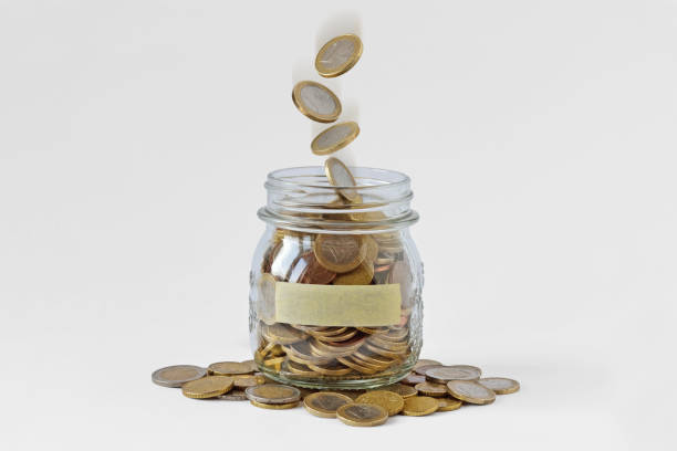 Money jar with blank label and falling coins on white background - Concept of economy and finance stock photo