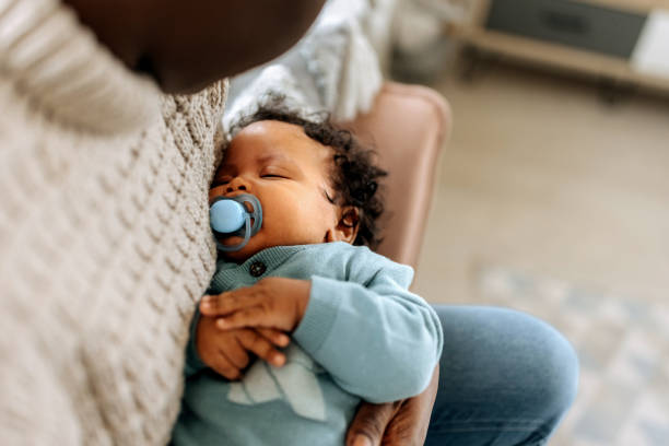 крупный план спящего ребенка на руках у матери - childrens music стоковые фото и изображения