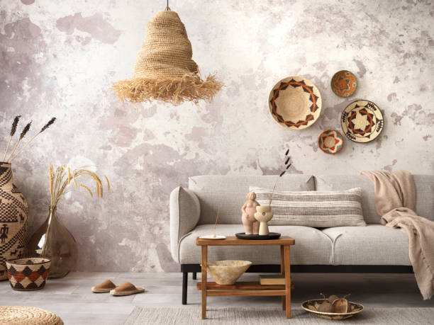 istock Interior design of ethnic composition living room interior with grey sofa, colorful wicker, boho straw lamp, gray concrete wall, bench and personal accessories. Home decor. Template. 1444109629
