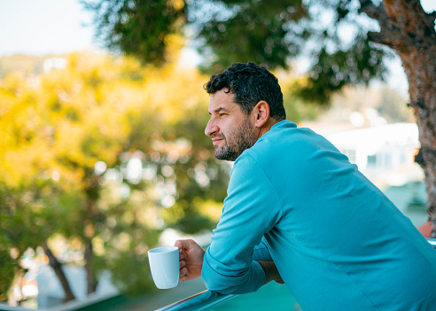 Meditative Man is Drinking Coffee on the Balcony