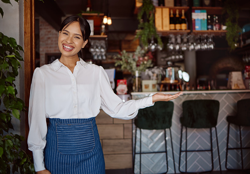 Welcome, restaurant waiter and business owner giving service with a smile at a coffee shop. Portrait of a black woman working as a waitress at a cafe, coffee shop or small business for fine dining
