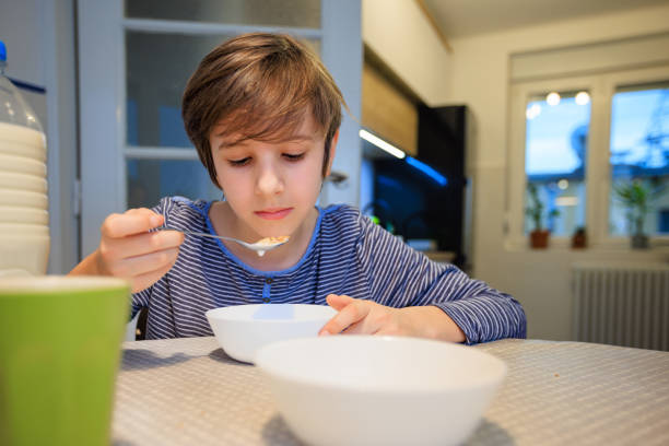 istock Preadolescent boy eating breakfast cereal at the table in the dining room 1444121226