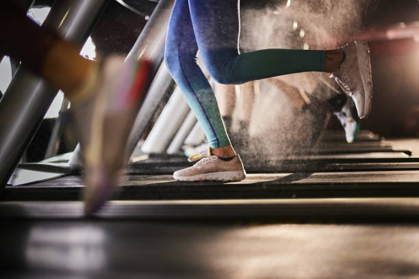 Unrecognizable athlete running on treadmill in a gym. Unrecognizable athletic woman exercising on treadmill in a health club. Copy space. treadmill stock pictures, royalty-free photos & images