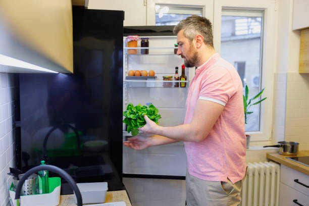 istock Man taking lettuce out from fridge to make healthy meal at home 1444121380