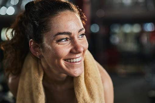 Happy female athlete with a towel after sports training in a gym.