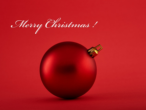 Red Christmas ball on red background with Merry Christmas text. Holiday, Christmas and new year concept