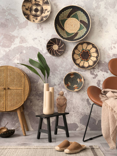 istock Creative composition of ethnic living room interior with colorful baskets, rattan sideboard, brown armchair and elegant personal accessories. Grey concrete wall. Home decor. Template. 1444122341