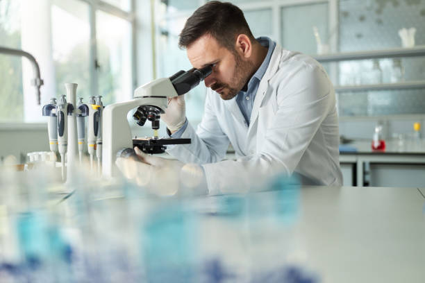 istock Young male chemist examining medical sample through a microscope in laboratory. 1444123635