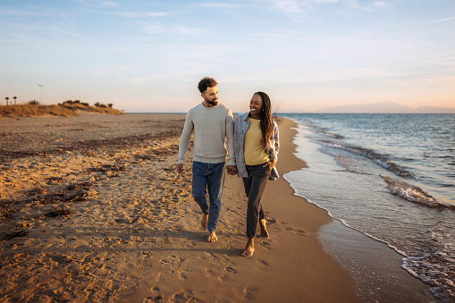 Young happy couple enjoys walk by the beach