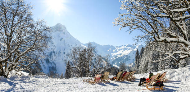 gruppe von personen, die mit liegestühlen im winterberge sitzen. ein sonnenbad im schnee. deutschland, bayern, allgäu, schwarzenberghuette. - apres ski snow winter european alps stock-fotos und bilder