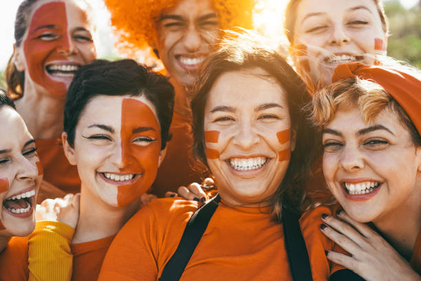 оранжевые спортивные болельщики кричат, поддерживая свою команду - футбольные болельщики веселятся на соревновательном мероприятии - соср - fan dutch flag women colors стоковые фото и изображения