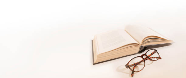 istock Long-sighted glasses and a big book. laying on a white background. Elderly eye health problems. 1444137255