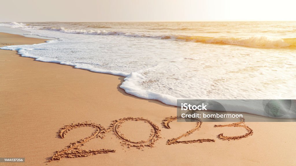 The year 2023- handwriting on sand beach, Happy New Year coming concept. White waves are lapping toward the shore. 2023 Stock Photo