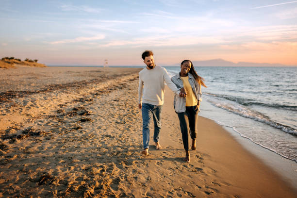 istock Young happy couple enjoys walk by the beach 1444137944