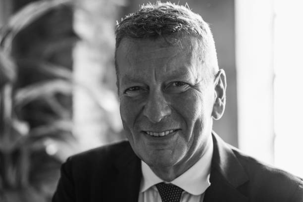 Happy senior business man working inside modern office - Focus on face - Black and white editing