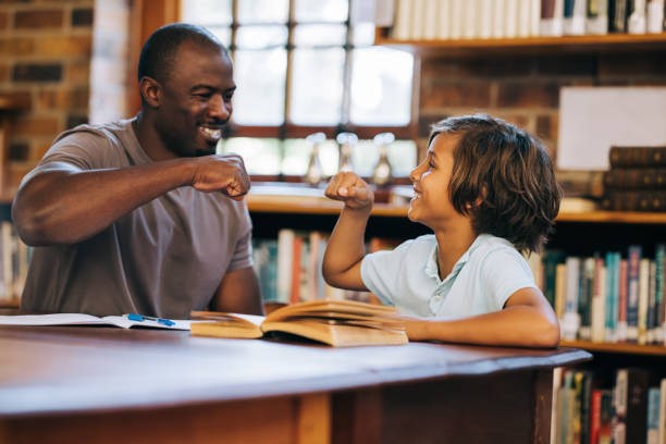 L’enseignant et l’élève se donnent un high five dans une bibliothèque - Photo