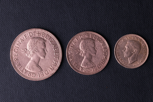 Haverfordwest, Wales - November 23, 2022: Studio shot of obsolete British one penny, half penny and farthing coins. The latter two were originally cut from a one penny coin, either into halves or quarters (fourthings). The farthing was phased out in 1960 and the larger penny and the mid-sized half penny went after UK decimalisation in 1971.