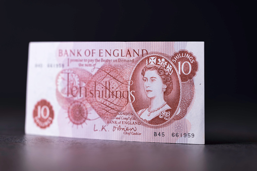 Haverfordwest, Wales - November 23, 2022: Studio shot of a UK pre-decimal ten shilling note. These were in use from 1928 until they became redundant from Monday February 15th 1971 - at which date the UK changed to decimal currency. The value of this banknote was equivalent to £0.50 in the 'new' currency. It was the smallest denomination banknote ever issued by the Bank of England.