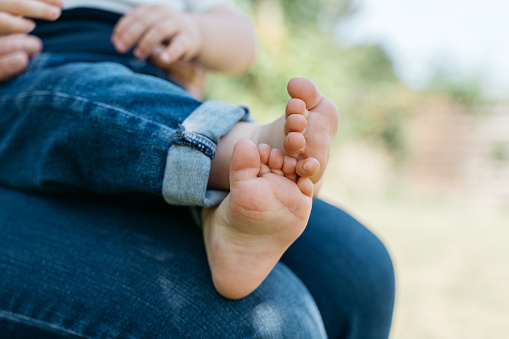 Close-up of the feet of a toddler sitting on someone's lap