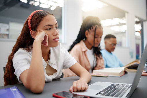 Mental health, studying and student with depression reading course information on laptop in library or university classroom. Sad, depressed and burnout college woman with exam problem or fail results