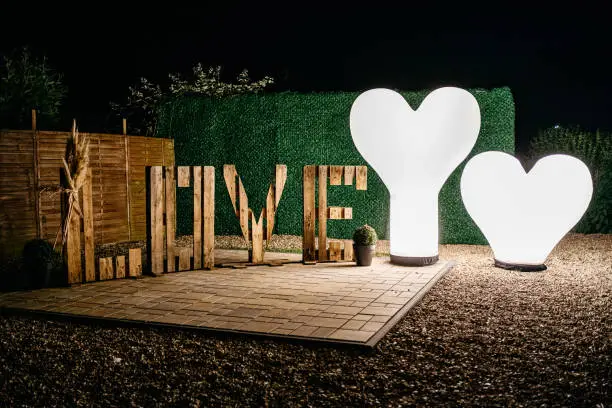 Word Love made out of wooden pallets next to two big heart shaped lights