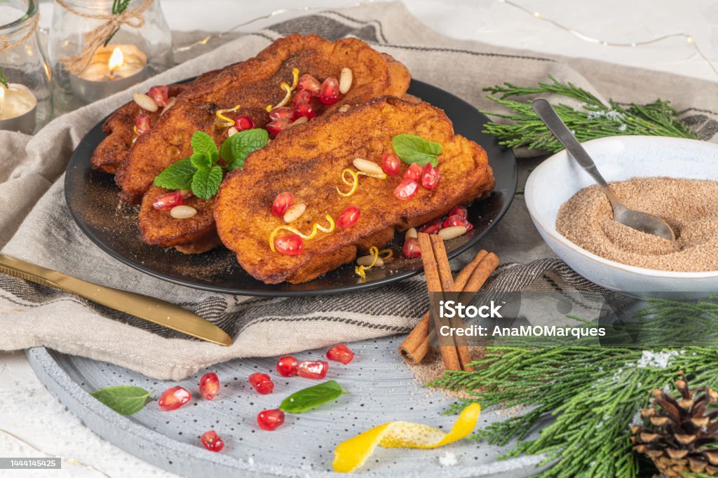 Traditional Christmas Rabanadas with lemon zest, pomegranate, pine nuts and cinnamon. Spanish Torrijas or french toasts close up on the countertop Bread Stock Photo