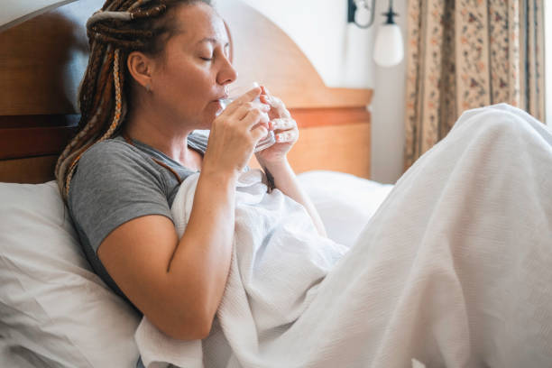 istock Woman sits in bed and drinks water. 1444147977