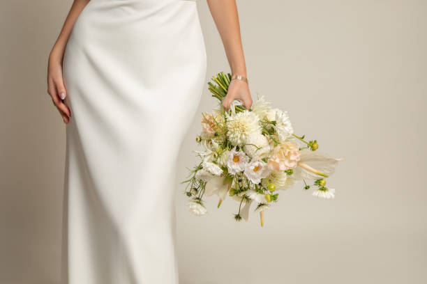 unrecognizable cropped woman in white elegant silk dress with white bouquet of natural flowers in hand with accessories - wedding dress bouquet wedding bride imagens e fotografias de stock